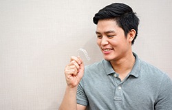 Young man holding Invisalign aligner in hand