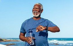 Senior man smiling while walking on beach path