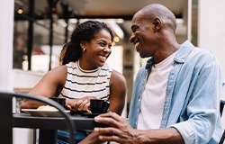 Couple smiling while enjoying cup of coffee outside