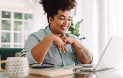 Woman smiling while working on laptop at home
