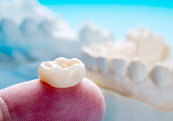 A closeup of a single dental crown on a finger