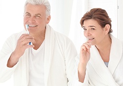 Older man and woman brushing teeth