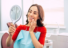 Woman in red shirt checking smile in mirror