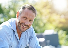 Man in -up shirt sitting outside and smiling