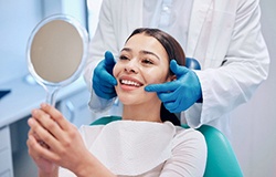 Woman smiling at reflection in dentist's mirror