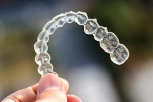 Outstretched hand holding a clear aligner for Invisalign in Bartlesville