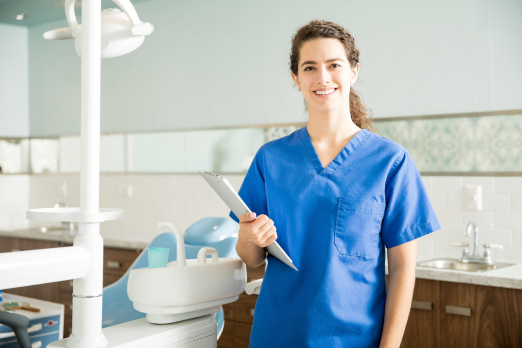 Woman wearing scrubs that are no longer worn in public to maintain dental office safety during COVID-19.