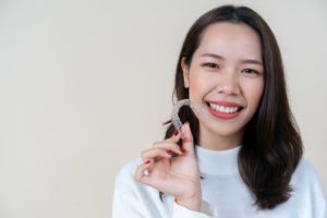 Woman holding Invisalign in Bartlesville while smiling