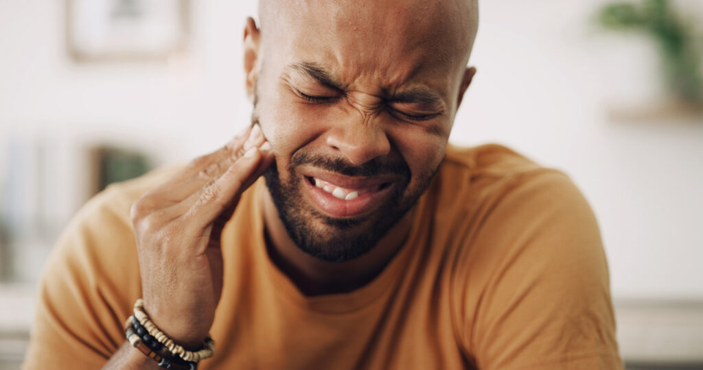 Man holding jaw in toothache pain.